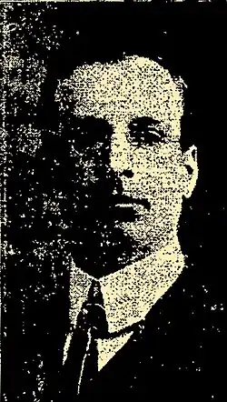 Black and white photo of a middle-aged man facing to the right, wearing a dark-coloured suit and a white dress shirt