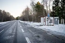 A snowy road near a bus stop.