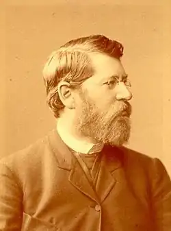 Sepia-tinted black-and-white portrait of Julius Zupitza, a bearded man with glasses facing right.