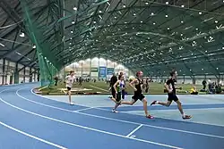 Indoor track and field facility with a group of runners circling the track