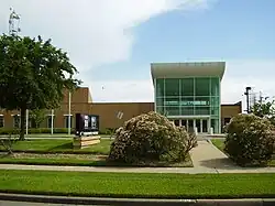 A stucco and glass building with a sign outside bearing the KRIV and KTXH logos.