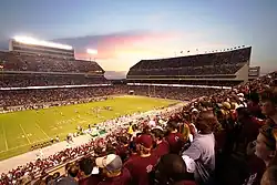 a crowd of people watch a football game at a three-tiered stadium