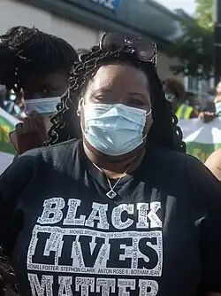 A Black woman wearing a surgical mask and a "Black Lives Matter" shirt