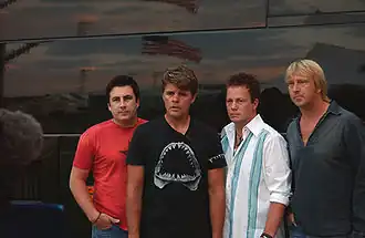 The four members of Lonestar, standing in front of a tour bus