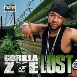 The cover features a man wearing a black tank top and hat, posing next to a green metal fence with barbed wire on top. Both the artist's name and song title appear below him, colored in white and green respectively.