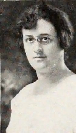 A white woman with dark curly hair and glasses