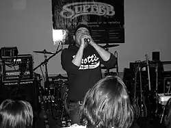 Black and white photograph of a man in a hoodie holding a microphone.