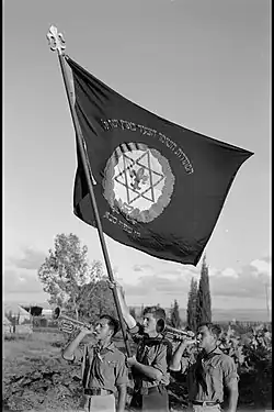 Members of Hashomer Hatzair in Kfar Saba branch blowing the trumpet as they wave the movement´s flag, 1941