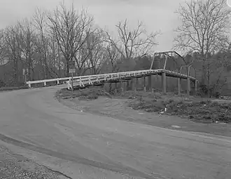 A monochromatic image of a truss bridge held up by stone pillars