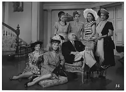 Film still. Man surrounded by women.