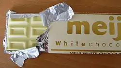 A chocolate wrapper labelled "meiji". Packaging is pulled back, and foil is torn to reveal chocolate beneath.