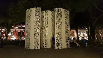 A pair of cylinders with tree-like cut-outs.