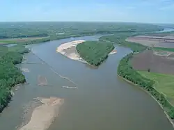Aerial view of a brownish river winding through an agricultural valley