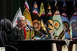 Mohammad Bagheri speaking with the Islamic Republic and military flags at the background.