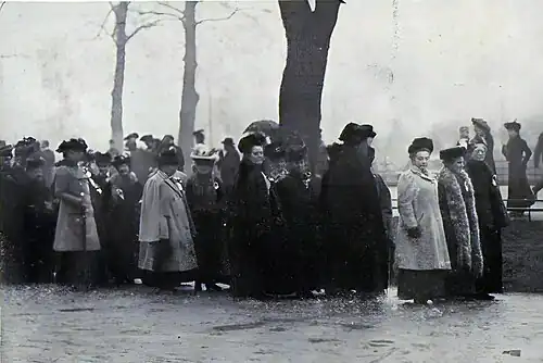 A group of marchers stand waiting in the rain.