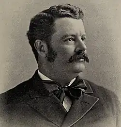 Black and white 1899 head and shoulders photo of Nathan Fellows Dixon III in suit and cravat, looking left