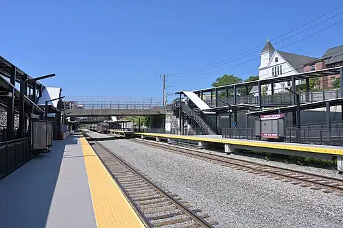 A railway station in an open cut with two high-level side platforms and long wheelchair ramps to the platforms