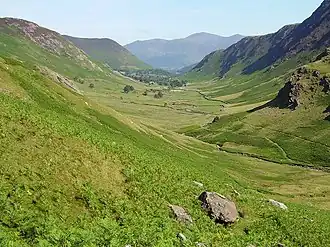 Outdoor countryside scene, with fells on either side of lush green valley