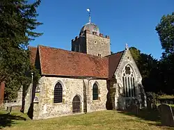 A stone church seen from the south, showing a transept with a large window, and a tower surmounted by a cupola