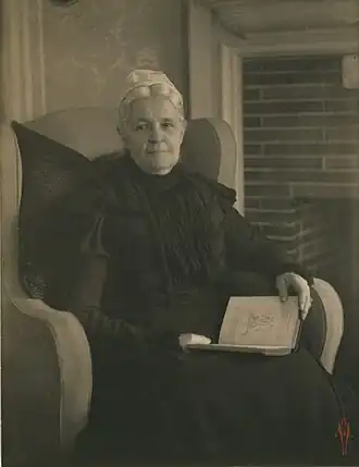 Old woman in an armchair, with an open book in her lap, ca. 1900