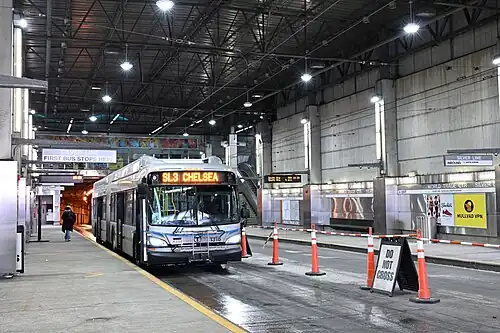 A silver bus inside a large bus station