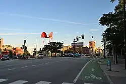 A slender white pole supporting three red, fan-like metal structures all on the same plane but twisted at different angles.