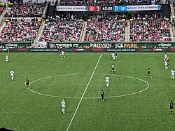 A view from the stands of Providence Park of Portland Thorns, in black football kit, and Chicago Red Stars, in white football kit, playing in front of an audience