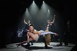 Dancer Urquiaga holding Melody after the final pirouette performed at the end of their performance at the PrePartyES, with dancers Bullón (left) and Montojo (right) in the background.