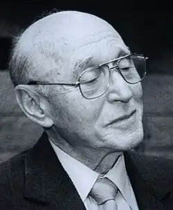 Photograph of an elderly man with grey hair, on a black background