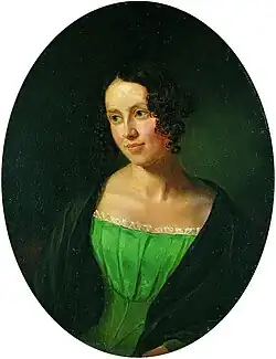Portrait of a young lady, over a black background. She is wearing a green dress, over a black coat. She is looking to the left, somewhat smiling.