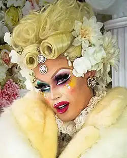 Photograph of a drag performer wearing a blond wig
