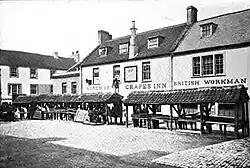 Monochrome photograph of the shambles standing on cobblestones. The Grapes Inn can be seen in the background.