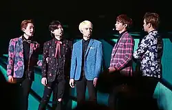 The five members of Shinee stand on stage together.