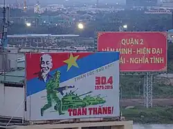 A billboard showing a Vietnamese soldier and tanks below Ho Chi Minh and the Viet Cong flag.