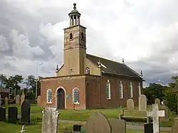 A Georgian style brick church seen from the southwest with a porch protruding in the foreground, a slim tower topped by a rotunda, and the body of the church extending beyond