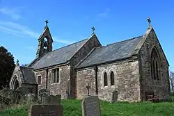 A stone church with chancel and a small bell-cot
