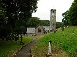Stone church with tall tower in grassed churchyard with gravestones