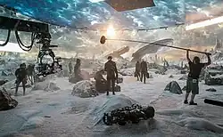 Picture of a film crew on a snow-covered set surrounded by screens that display a background of snow and clouds