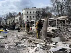 Aftermath of Sumy airstrikes, with fatalities present on the left side of the image amid several rescue personnel and burnt out vehicles and a bus in Sumy City center during the day