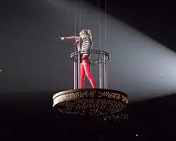 Swift pointing to the audience while standing in a flying cage