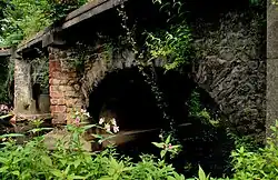 Close-up of three low stone and brick arches over running water.
