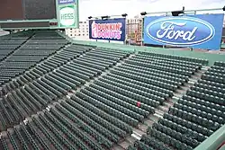 The Red Seat is seen completely surrounded by dark green seats in center field and right field in Fenway Park.