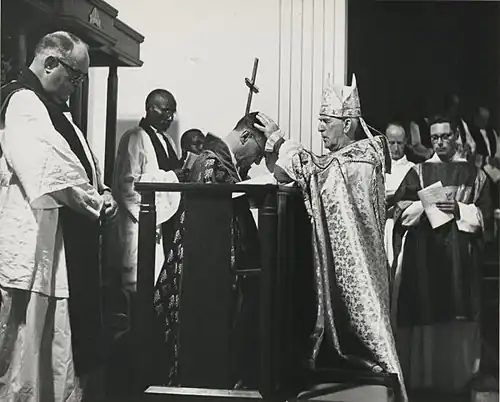kneeling man being blessed by standing man, the latter in cope and mitre