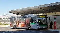 Picture of Transperth 2359 (Volvo B7RLE/Volgren Optimus) at the High Wycombe railway station in Perth, Australia, with a promotional poster featuring the Flash, Batman, and Supergirl in their costumes and the film's tagline "Worlds Collide".