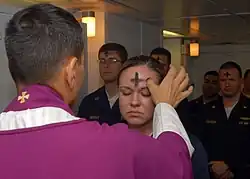 A priest marks a cross of ashes on a worshipper's forehead.