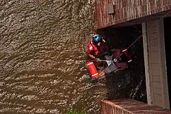 A Coast Guard Aviation Survival Technician assisting with the rescue of a pregnant woman during Hurricane Katrina in 2005