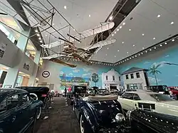 Antique airplane hanging above the vintage automobile exhibit at the Elliott Museum