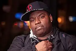 A picture of the Ballroom Icon DJ Vjuan Allure wearing a black cap and a sweatshirt