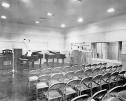 Radio studio with microphones, two grand pianos and folding chairs for an audience