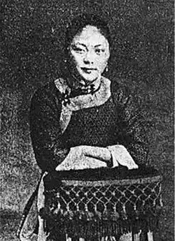A black-and-white picture of a young woman leaning over a table